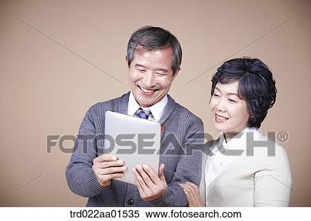 Stock Photography - A old man and old woman looking at tablet PC. Fotosearch