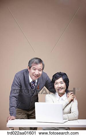 Stock Image - A smiling old man and old woman with laptop. Fotosearch