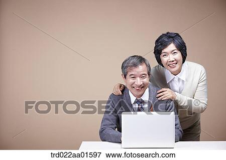 Stock Photo - A smiling old man and old woman with laptop. Fotosearch