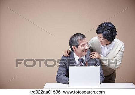 Stock Photograph - A smiling old man and old woman with laptop. Fotosearch