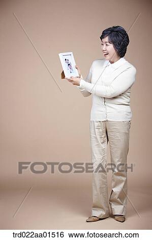 A smiling old woman with family photograph View Large Photo Image Stock Photograph - A smiling old woman with family photograph. Fotosearch
