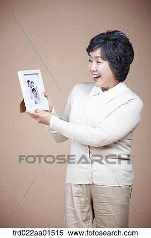 A smiling old woman with family photograph View Large Photo Image Stock Photography - A smiling old woman with family photograph. Fotosearch