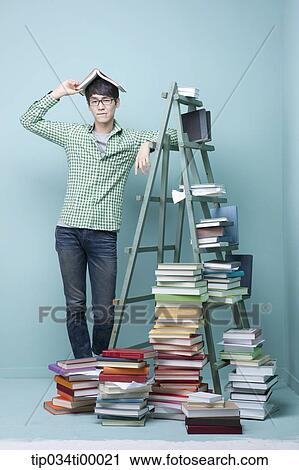 Stock Image - A studying man by the piled books and ladder. Fotosearch