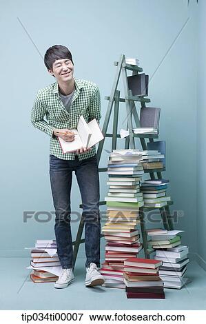 Stock Photo - A studying man by the piled books and ladder. Fotosearch