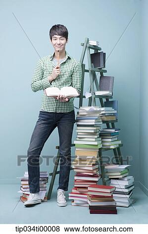 Stock Photo - A studying man by the piled books and ladder. Fotosearch