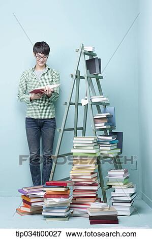Stock Photo - A studying man by the piled books and ladder. Fotosearch