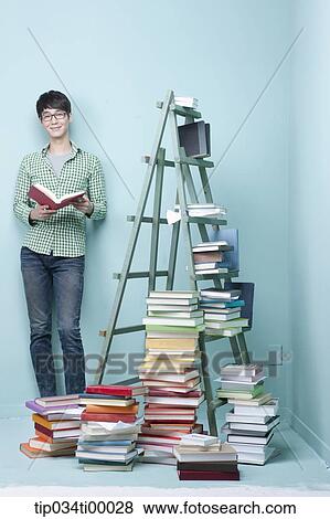 A studying man by the piled books and ladder View Large Photo Image Stock Photo - A studying man by the piled books and ladder. Fotosearch