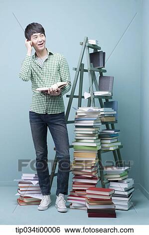 Stock Photograph - A studying man by the piled books and ladder. Fotosearch