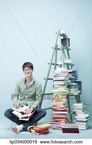 Stock Photograph - A studying man by the piled books and ladder. Fotosearch