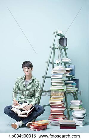 Stock Photography - A studying man by the piled books and ladder. Fotosearch