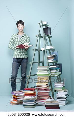 Stock Photography - A studying man by the piled books and ladder. Fotosearch
