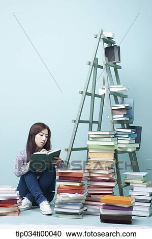 Stock Image - A studying woman by the piled books and ladder. Fotosearch