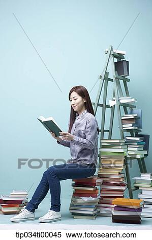 Stock Photography - A studying woman on the piled books. Fotosearch