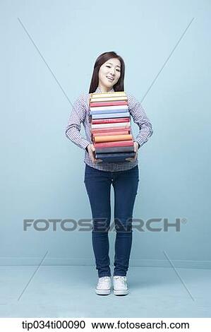 Stock Image - A woman carrying the pile of books. Fotosearch