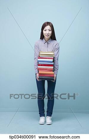 Stock Image - A woman carrying the pile of books. Fotosearch