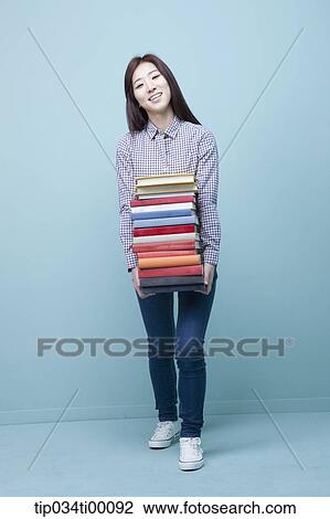 Stock Image - A woman carrying the pile of books. Fotosearch