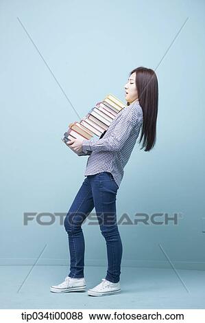 Stock Photo - A woman carrying the pile of books. Fotosearch