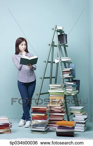 A woman reading a book by the piled books and ladder View Large Photo Image Stock Photograph - A woman reading a book by the piled books and ladder. Fotosearch