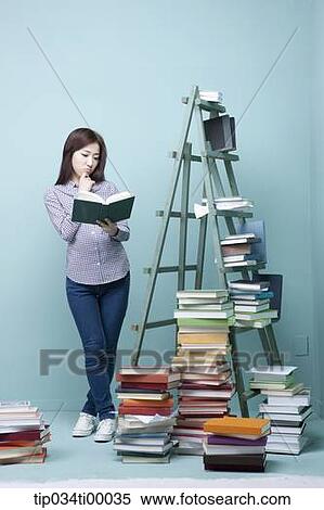 A woman reading a book by the piled books and ladder View Large Photo Image Stock Photography - A woman reading a book by the piled books and ladder. Fotosearch