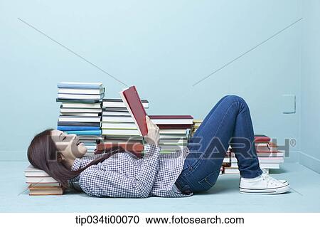 Stock Image - A woman reading a book on the floor. Fotosearch