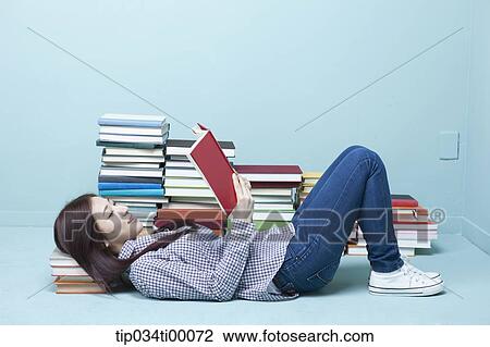 Stock Image - A woman reading a book on the floor. Fotosearch