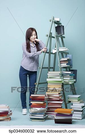 A woman worrying about the piled books View Large Photo Image Stock Image - A woman worrying about the piled books. Fotosearch