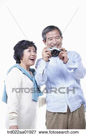 An old couple photographing with camera View Large Photo Image Stock Photo - An old couple photographing with camera. Fotosearch
