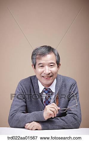 Stock Photo - An old man holding the glasses. Fotosearch