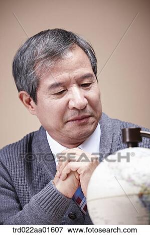 An old man looking at the globe seriously View Large Photo Image Stock Photo - An old man looking at the globe seriously. Fotosearch