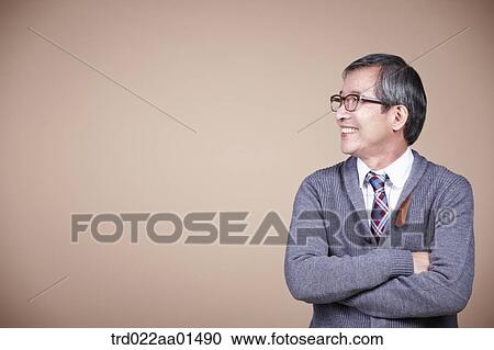 Stock Image - An old man looking at the right side with his arms folded. Fotosearch