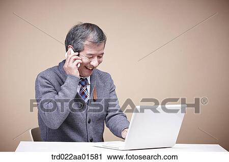 An old man talking on the phone with the laptop around View Large Photo Image Stock Image - An old man talking on the phone with the laptop around. Fotosearch