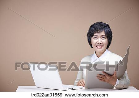 An old woman looking at document with laptop around View Large Photo Image Stock Photo - An old woman looking at document with laptop around. Fotosearch