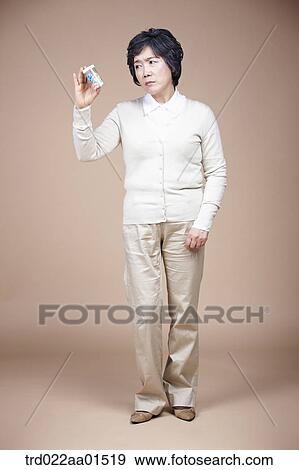 Stock Photo - An old woman looking at medicine seriously . Fotosearch