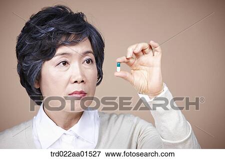 Stock Photo - An old woman looking at pill. Fotosearch