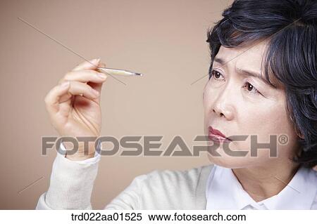 An old woman looking at thermometer seriously View Large Photo Image Stock Photography - An old woman looking at thermometer seriously . Fotosearch