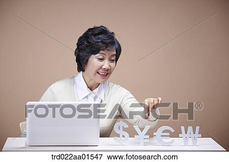 An old woman picking up foreign currency with laptop around View Large Photo Image Stock Photo - An old woman picking up foreign currency with laptop around. Fotosearch