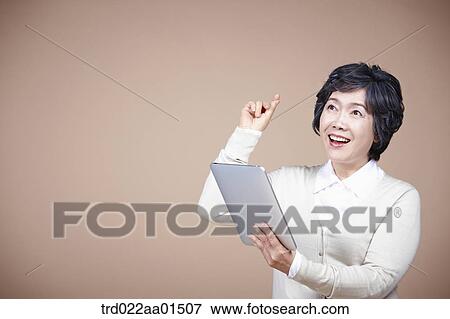 Stock Photo - An old woman thinking of idea with tablet PC. Fotosearch