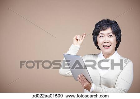 Stock Photo - An old woman thinking of idea with tablet PC. Fotosearch