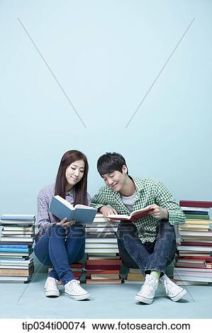 Studying man and woman between the piled books View Large Photo Image Picture - Studying man and woman between the piled books. Fotosearch