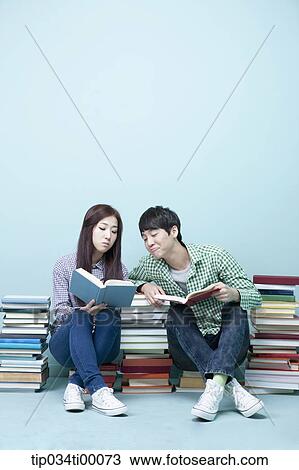 Studying man and woman between the piled books View Large Photo Image Stock Image - Studying man and woman between the piled books. Fotosearch