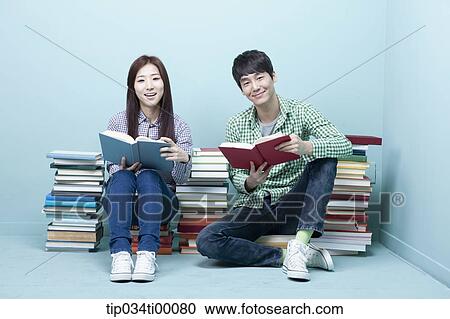 Studying man and woman between the piled books View Large Photo Image Stock Image - Studying man and woman between the piled books. Fotosearch