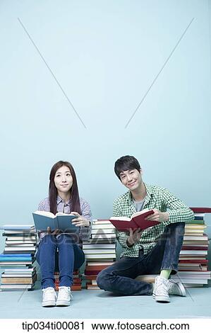 Stock Image - Studying man and woman between the piled books. Fotosearch