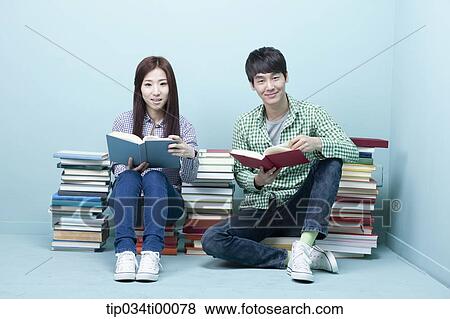 Stock Photo - Studying man and woman between the piled books. Fotosearch
