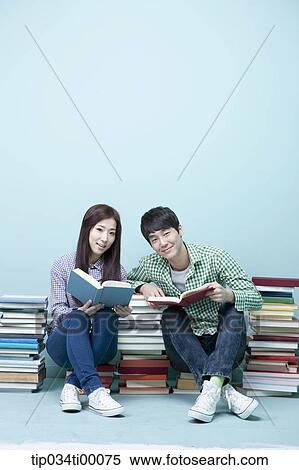 Stock Photography - Studying man and woman between the piled books. Fotosearch