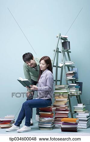 Studying man and woman by the piled books View Large Photo Image Stock Photo - Studying man and woman by the piled books. Fotosearch