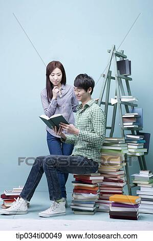 Stock Photo - Studying man and woman by the piled books. Fotosearch