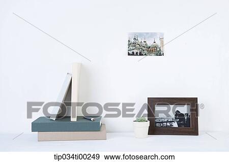 Stock Photo - The book, pot, frame, and photograph on the wall. Fotosearch