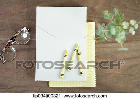 Stock Image - The glasses, crayon on the book, and green plant in glass. Fotosearch
