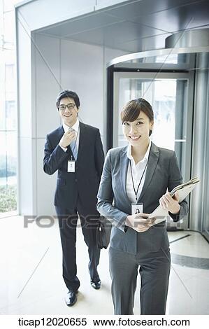 A business man and a business woman walking into an office building View Large Photo Image Stock Photography - A business man and a business woman walking into an office building. Fotosearch