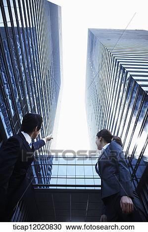 A business man with a business woman pointing at the roofs of joined office buildings View Large Photo Image Stock Image - A business man with a business woman pointing at the roofs of joined office buildings. Fotosearch